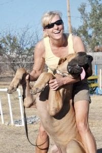 A woman holding onto the back of a dog