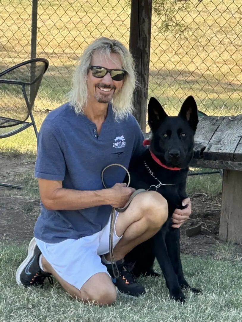 A man kneeling down next to his dog.