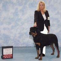 A woman standing next to a dog in front of a sign.