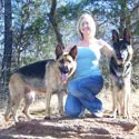 A woman kneeling down next to two dogs.